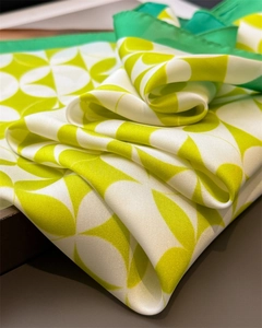 Detailed view of green and white geometric pattern satin silk scarf with rolled edges