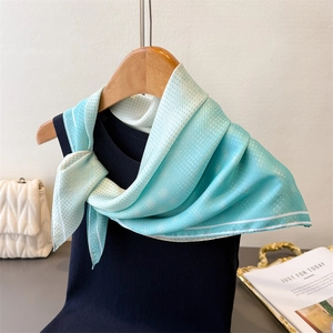 Detail of light blue silk-like scarf with white polka dots on a blue knit top