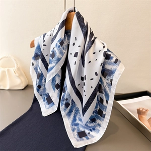 Carré de soie élégant imprimé zèbre avec motifs géométriques bleus sur cintre en bois