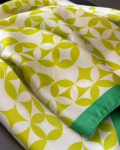 Detailed macro view of the smooth satin texture and green floral pattern on the silk scarf