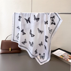 Detail of white silk scarf showing black butterfly prints and elegant black line borders