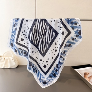 Détail d'un foulard en soie à motif zèbre et bords géométriques bleus sur un support