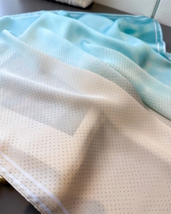 Detailed close-up of blue-white gradient silk scarf with polka dots and striped edges