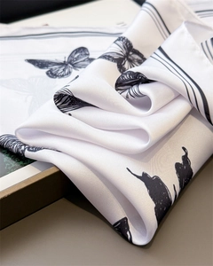 Macro detail of silk satin scarf featuring elegant black butterfly patterns and soft texture