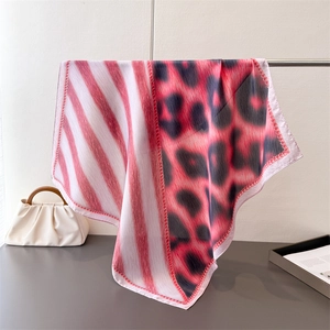 Detail of red striped and pink leopard print faux silk scarf with fine red edge stitching