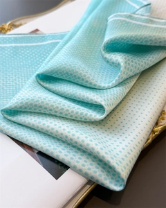 Detail of light green silk scarf featuring delicate white polka dots and elegant texture