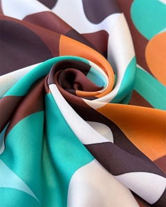 Détail macro du foulard en soie géométrique montrant le fini satiné et l'imprimé abstrait