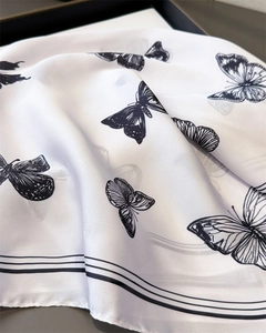 Detailed view of lightweight silk scarf featuring black butterfly prints and fine striped edges