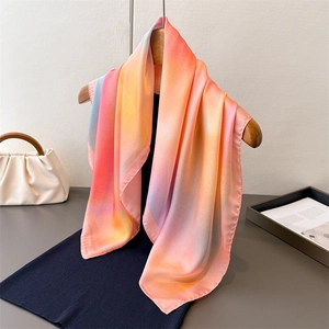 Elegant gradient satin silk square scarf in pastel tones hanging on a wooden hanger