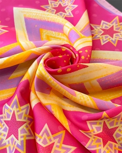 Macro detail of geometric star patterns on a pink and yellow silk scarf fabric