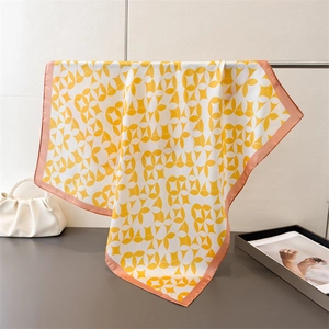 Detail of elegant satin square scarf with yellow geometric print and pink hem