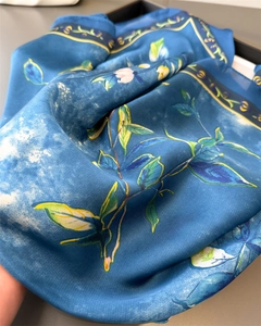 Detail of elegant blue floral silk scarf showing soft satin texture and leaf print