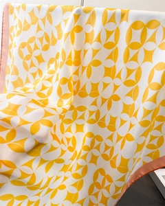 Detail showing bright yellow geometric pattern on silk scarf with premium hand-rolled edges
