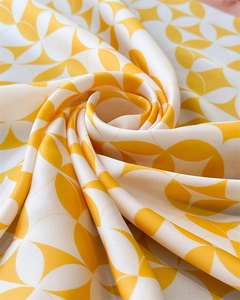 Detailed view of yellow and white geometric pattern on silky satin scarf fabric