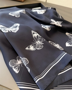 Macro shot of dark silk scarf featuring white butterfly prints and striped borders