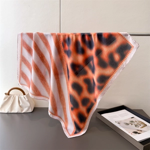 Detail showing high-quality leopard print silk scarf with orange stripes and smooth texture