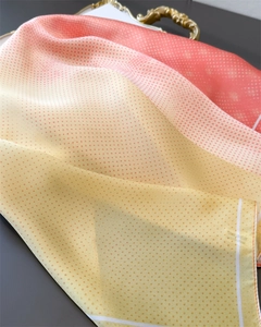 Macro detail of silk scarf featuring yellow-orange gradient with red polka dot pattern