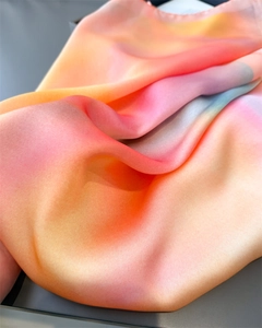 Macro shot of gradient silk-like scarf fabric showing soft drape and vibrant colors