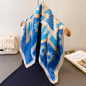 Elegant royal blue geometric pattern silk scarf styled with a black dress and accessories