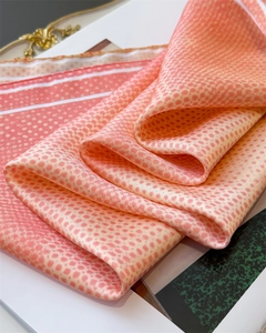 Detail of pink silk scarf showing peach polka dot pattern and smooth satin texture