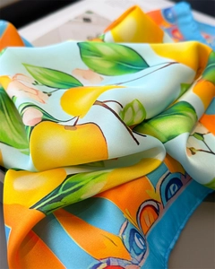 Detailed close-up of sky blue silk scarf featuring vibrant yellow citrus and leaf prints