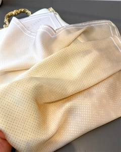 Close-up of champagne silk scarf with fine polka dots and smooth satin texture