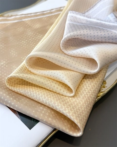 Close-up of printed silk scarves with gradient patterns on a luxury gold tray