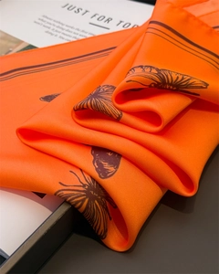 Macro detail of silk-feel scarf with butterfly print and luxury satin texture on magazine