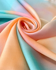 Close-up of rainbow gradient silk scarf showing soft fabric texture and spiral draping