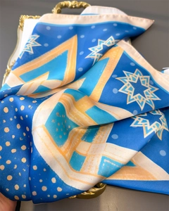 Detail of geometric vintage silk-like scarf with Klein blue stars and golden pattern