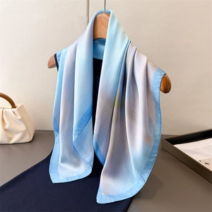 Blue gradient silk scarf on wooden hanger paired with deep blue dress for styling