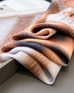 Detailed close-up of glossy leopard print silk scarf with luxury textured abstract patterns