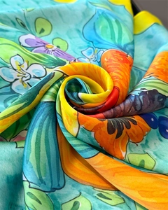 Detail of vibrant floral silk scarf with colorful lily prints and a smooth satin texture
