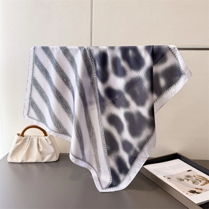 Detail of silk-like leopard print square scarf featuring asymmetric stripes and patterns