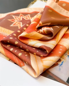 Detail of silk-like scarf with vintage geometric star patterns in warm orange and brown