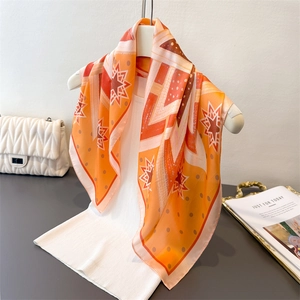 Vintage orange silk scarf with geometric star patterns hanging on a white tank top