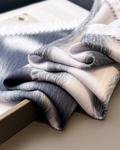 Macro shot of grey silk scarf with elegant wave texture on a minimalist wooden tray