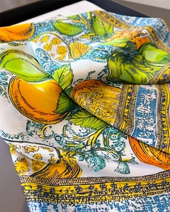 Detail view of vibrant silk scarf with lemon and tropical leaf print and smooth texture