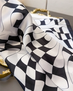 Close-up of silk-like square scarf with distorted black and white checkerboard pattern