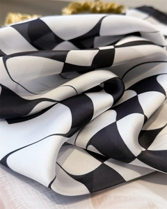 Macro detail of silk-like satin square scarf with black and white wavy geometric patterns