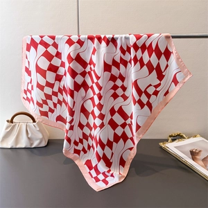 Detail view of red and white checkered silk scarf draped on a metal display stand