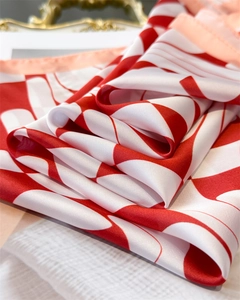 Detail of red and white wavy geometric silk scarf showing glossy texture and hem
