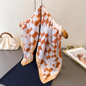 Orange and white checkered silk-feel square scarf hanging on a wooden hanger with a handbag