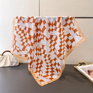 Detailed view of warped checkerboard silk scarf with orange and white geometric patterns