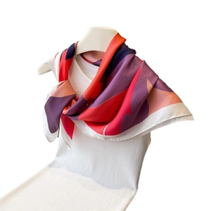 Silk satin square scarf with colorful abstract geometric patterns on a white top