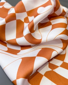 Macro shot of silk-like satin scarf with orange and white checkered pattern textures