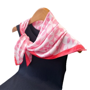 Pink and white silk-like scarf with geometric floral print on a black vest
