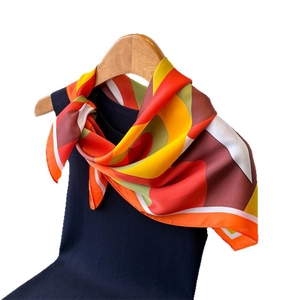 Foulard en soie avec motifs géométriques colorés porté sur un haut bleu foncé fond blanc pur