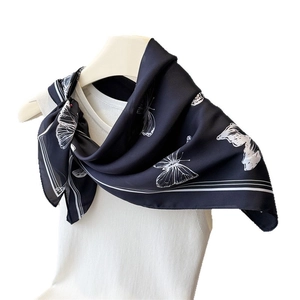 Elegant black silk-like scarf with white butterfly print on white knit top