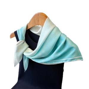 Light blue floral print silk scarf with white polka dots on a wooden hanger display